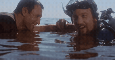 Two Men Swimming In Ocean One Wearing Goggles GIF
