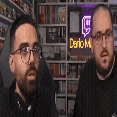 Two Men Talking In Front Of Dario M Sign GIF