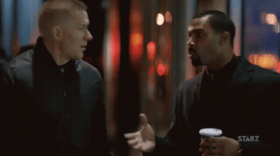 Two Men Talking In Front Of Starz Logo GIF