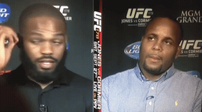 Two Men Talking In Front Of UFC Sign GIF