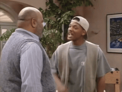 Two Men Talking In Living Room, One Wearing Hat GIF