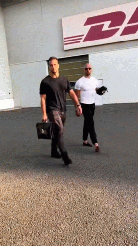 Two Men Walk In Front Of DHL Sign GIF