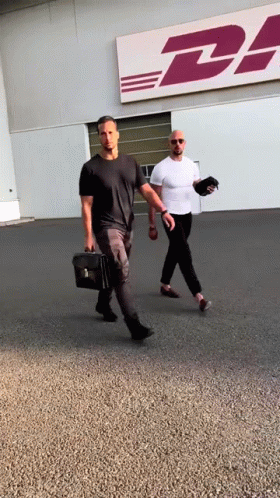Two Men Walking In Front Of DHL Building GIF