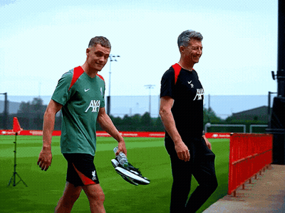 Two Men Walking On Field, One Wearing AXA Shirt GIF