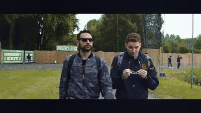 Two Men Walking Past Emergency Exit Sign GIF