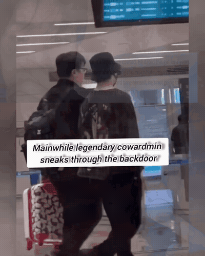 Two Men Walking Through Airport While Legendary Cowardmin Sneaks Through Backdoor GIF