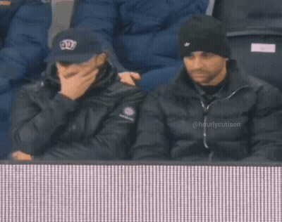 Two Men Watching Game Man In Crown Hat GIF
