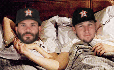 Two Men Wearing Astros Hats Are Laying In Bed Together GIF