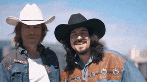 Two Men Wearing Cowboy Hats And Denim Jackets Pose For A Picture GIF