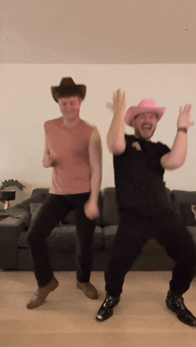 Two Men Wearing Cowboy Hats Are Dancing In Front Of A Couch GIF