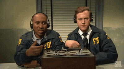 Two Men Wearing Fbi Uniforms Are Sitting At A Desk GIF