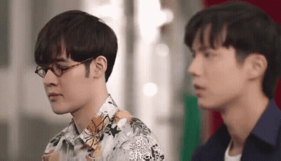 Two Men Wearing Glasses Are Standing Next To Each Other And Looking At Each Other . GIF