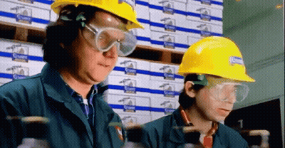 Two Men Wearing Hard Hats And Goggles Are Working In A Warehouse With Boxes Behind Them GIF