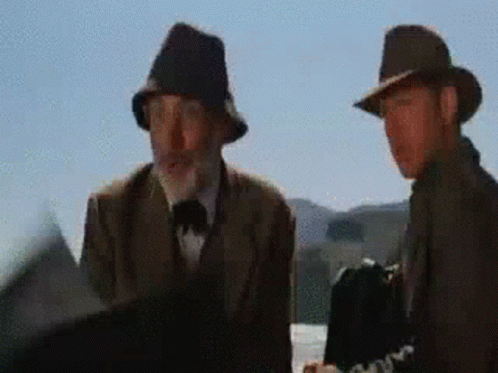 Two Men Wearing Hats Are Standing Next To Each Other And Talking GIF