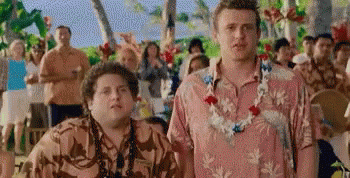 Two Men Wearing Hawaiian Shirts And Lei Are Standing Next To Each Other In Front Of A Crowd Of People . GIF