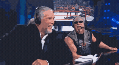 two men wearing headphones are laughing in front of a screen with a wrestling match on it