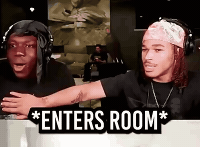 Two Men Wearing Headphones Are Sitting In Front Of A Sign That Says " Enters Room " . GIF