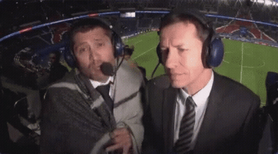 Two Men Wearing Headphones Are Talking To Each Other In A Stadium . GIF