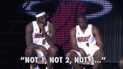Two Men Wearing Heat Jerseys Are Sitting On A Stage GIF