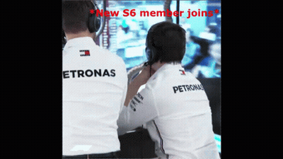 Two Men Wearing Petronas Shirts Are Looking At Something GIF