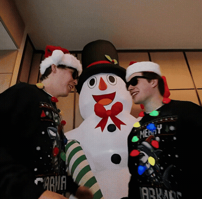 Two Men Wearing Santa Hats And Sweaters That Say Merry GIF