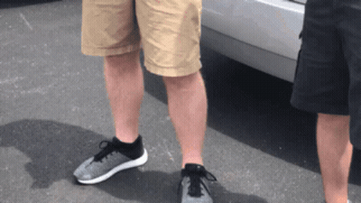 Two Men Wearing Shorts And Sneakers Are Standing Next To Each Other In Front Of A Car GIF