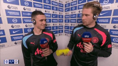 Two Men Wearing Sky Sports Shirts Are Talking To Each Other GIF
