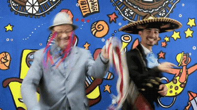 Two Men Wearing Sombrero Hats Are Dancing In Front Of A Mural That Says ' Fiesta ' GIF