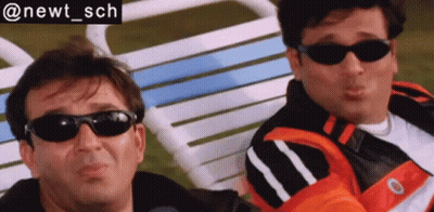 Two Men Wearing Sunglasses Sit Next To Each Other In A Chair GIF