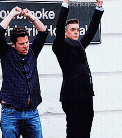 Two Men With Arms Up At Karaoke GIF