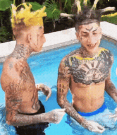 Two Men With Tattoos Sitting In Swimming Pool One With Crown GIF