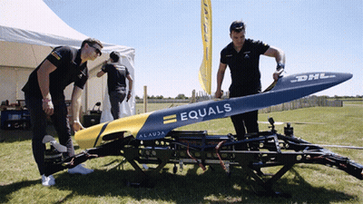 Two Men Working On Drone In Grass GIF