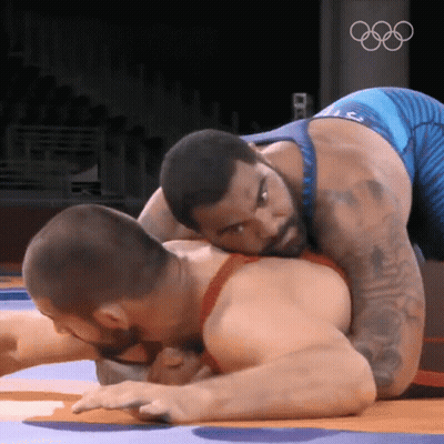 Two Men Wrestling In Front Of Olympic Logo GIF