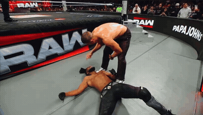 Two Men Wrestling In Front Of Papa Johns Banner GIF