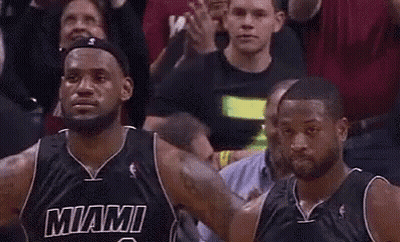 Two Miami Heat Basketball Players Are Standing Next To Each Other In Front Of A Crowd During A Game . GIF