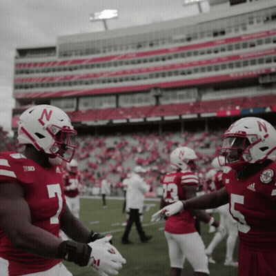 Two Nebraska Football Players Shake Hands In Front Of Stadium GIF