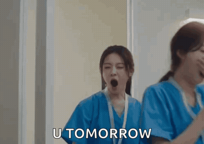 Two Nurses Yawning In Hallway While Another Says U Tomorrow GIF
