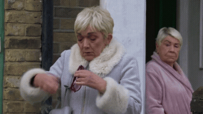 Two Older Women Are Standing Next To Each Other In Front Of A Brick Building . GIF