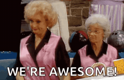 Two Older Women In Pink Shirts Are Sitting At A Table With Bowling Balls . GIF