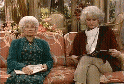 Two Older Women Sitting On Couch Reading Magazines GIF