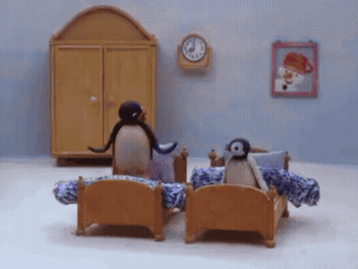 Two Penguins Sitting On Bed GIF