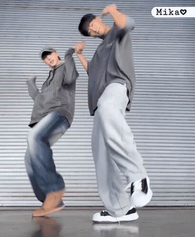 Two People Are Dancing In Front Of A Wall And The Word Mika Is On The Bottom GIF