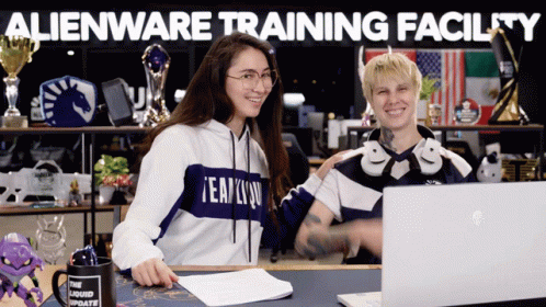 Two People Are Sitting In Front Of A Laptop With The Words Alienware Training Facility Written Above Them GIF