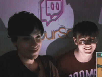 Two People Are Smiling In Front Of A Sign That Says Urs GIF