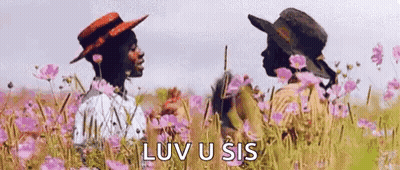 Two People Are Standing In A Field Of Flowers . GIF