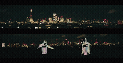 Two People Are Standing In Front Of A City At Night GIF