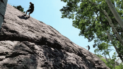 Two People Climbing Rocky Cliff GIF