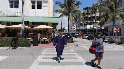 Two People Crossing Street In Front Of Majesty Restaurant GIF