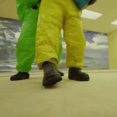 Two People In Green And Yellow Suits Walking GIF