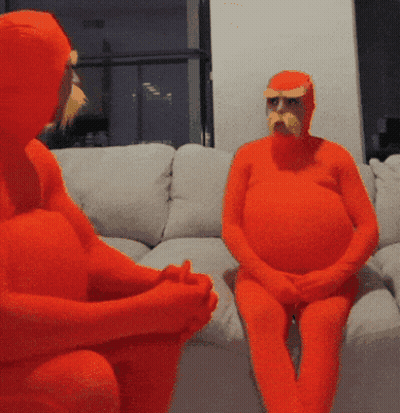 Two People In Orange Costumes Are Sitting On A Couch With Their Hands Folded GIF